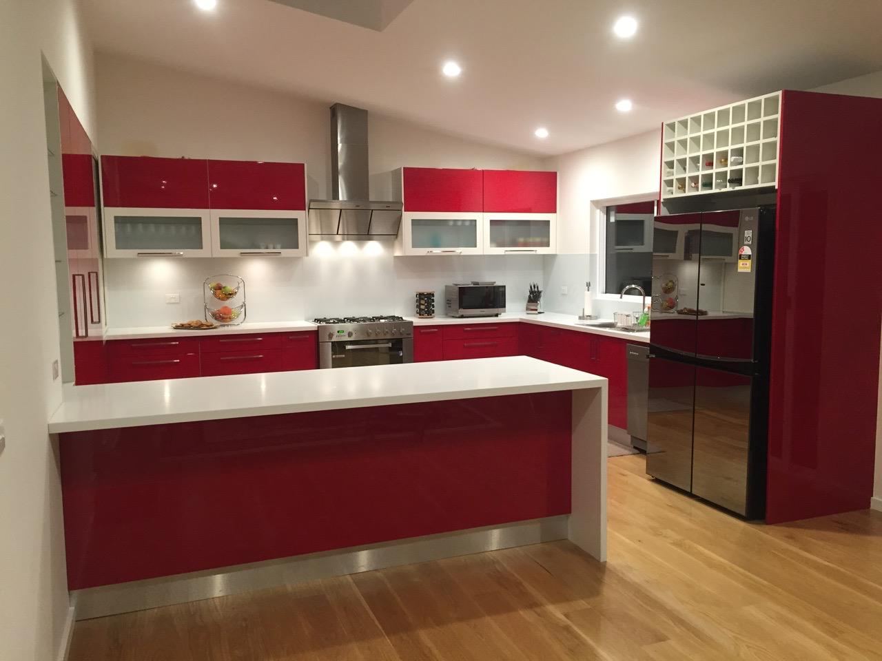 High-gloss red kitchen with white benchtop manufactured by Oktay Cabinets